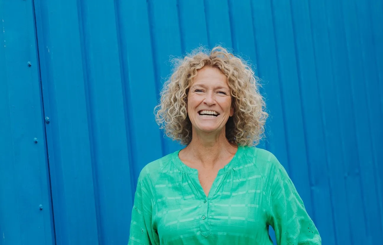 Woman with blonde curls in front of a blue container at BLOOS