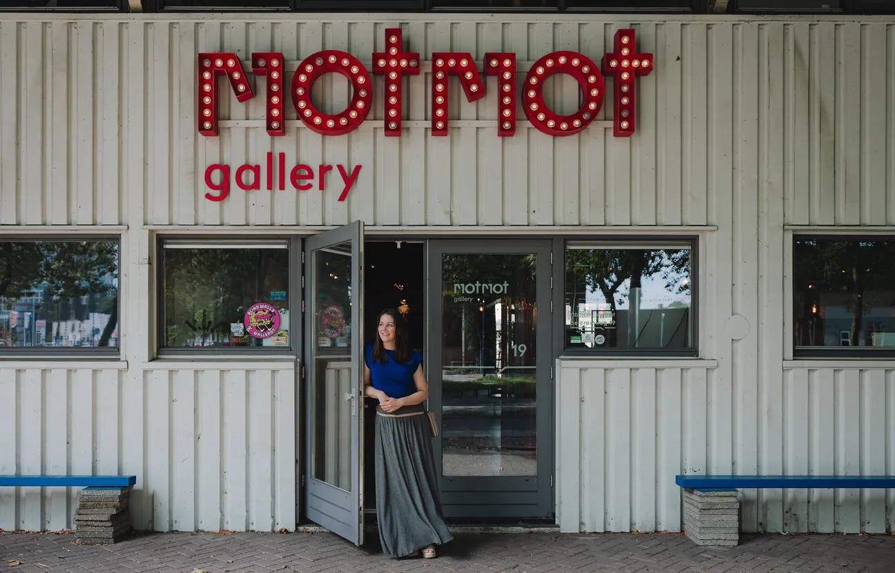 A woman leaning against a wall at MOTMOT Gallery