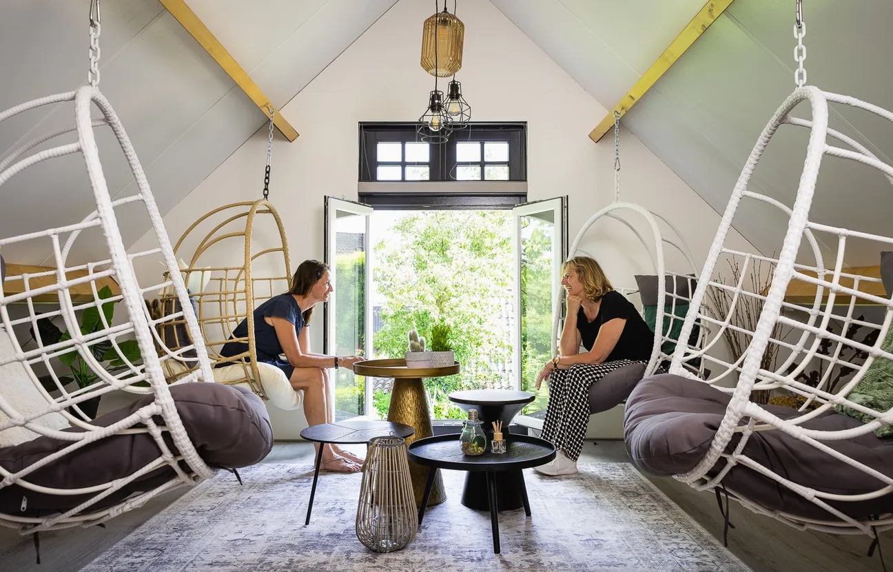 Twee vrouwen in gesprek in hangende stoelen