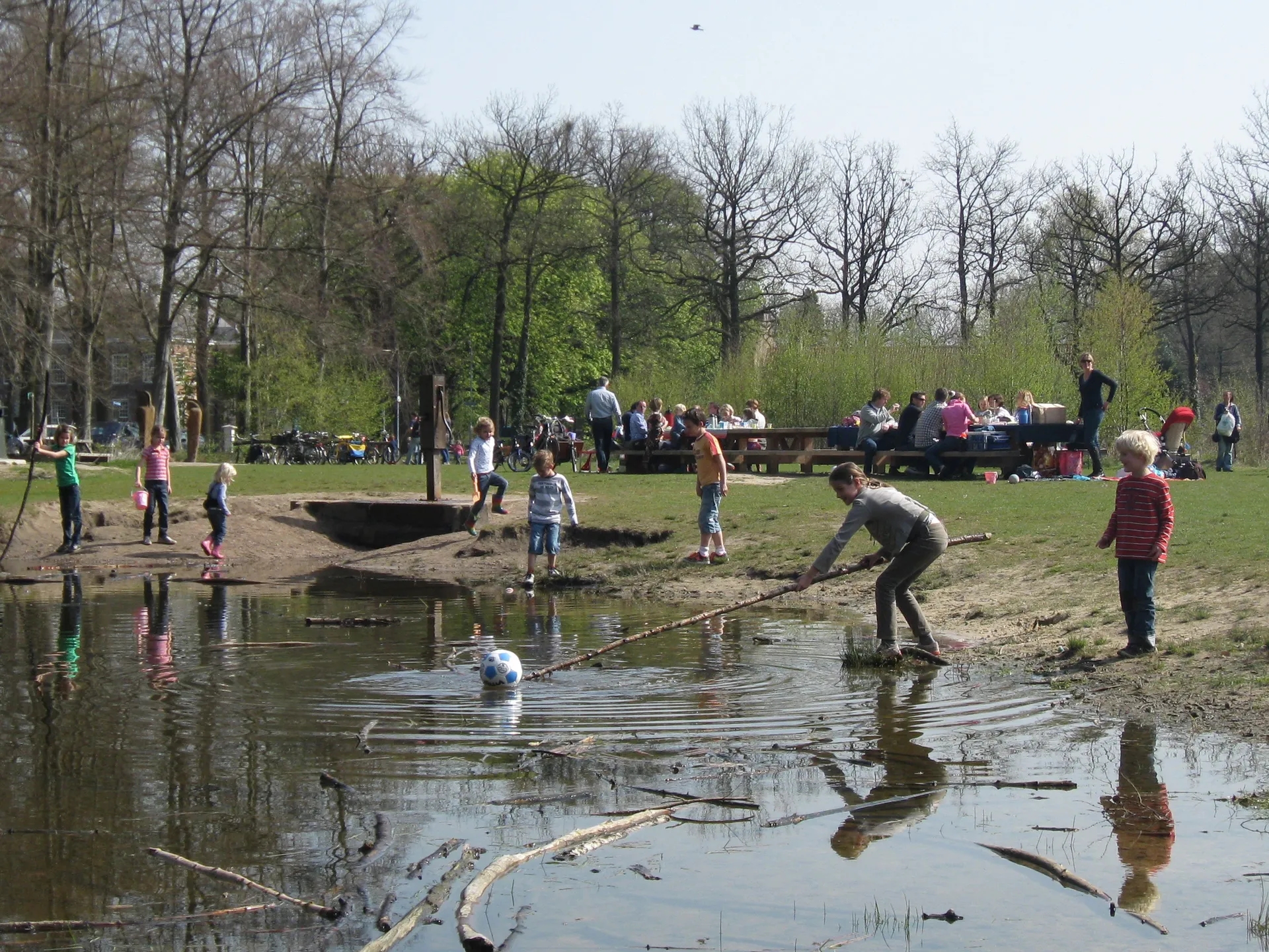 kleine waterplas in het speelbos waar kinderen in en naast het water spelen