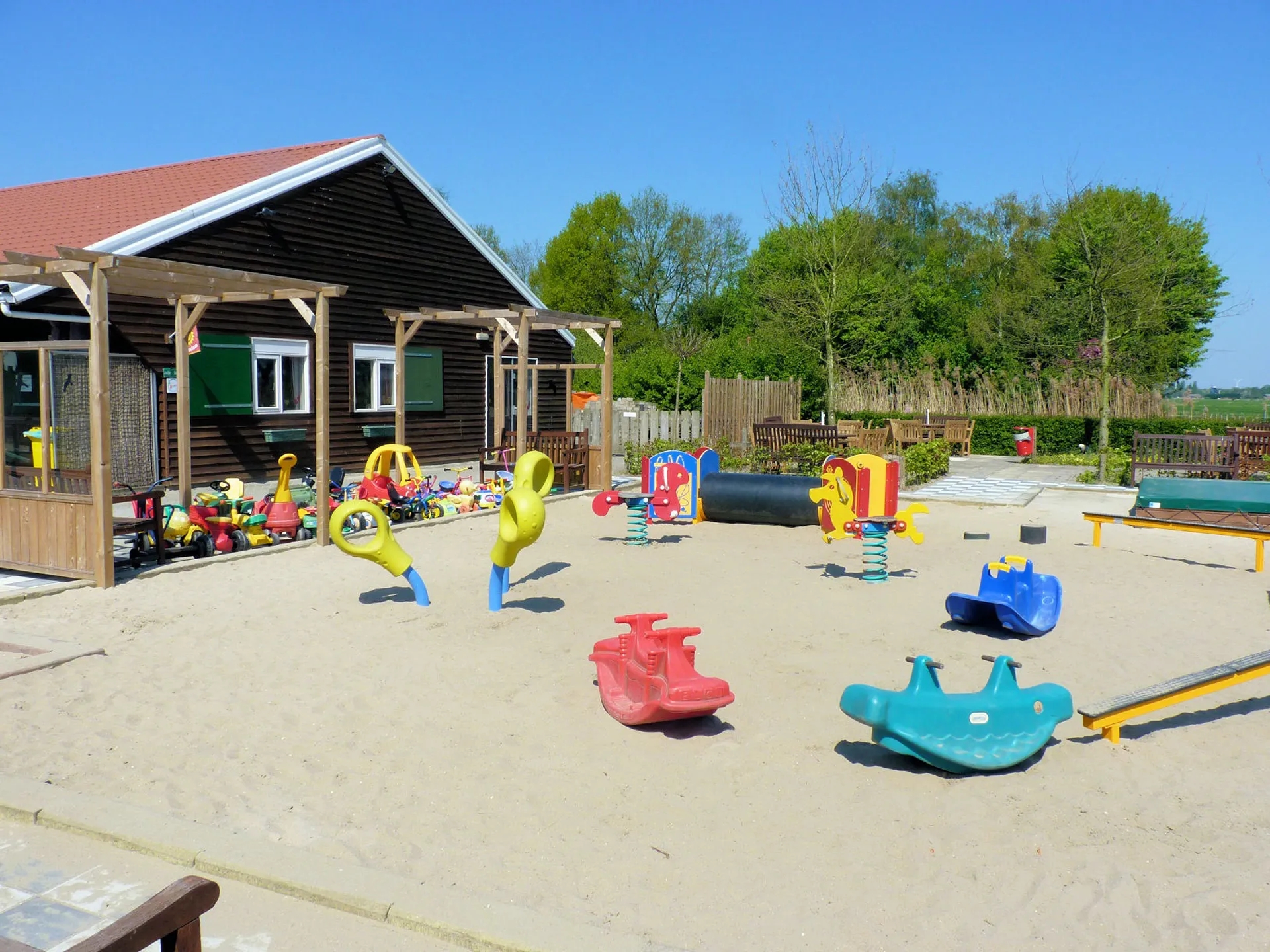 Speeltuin naast kinderboerderij met zandbak en speeltoestellen