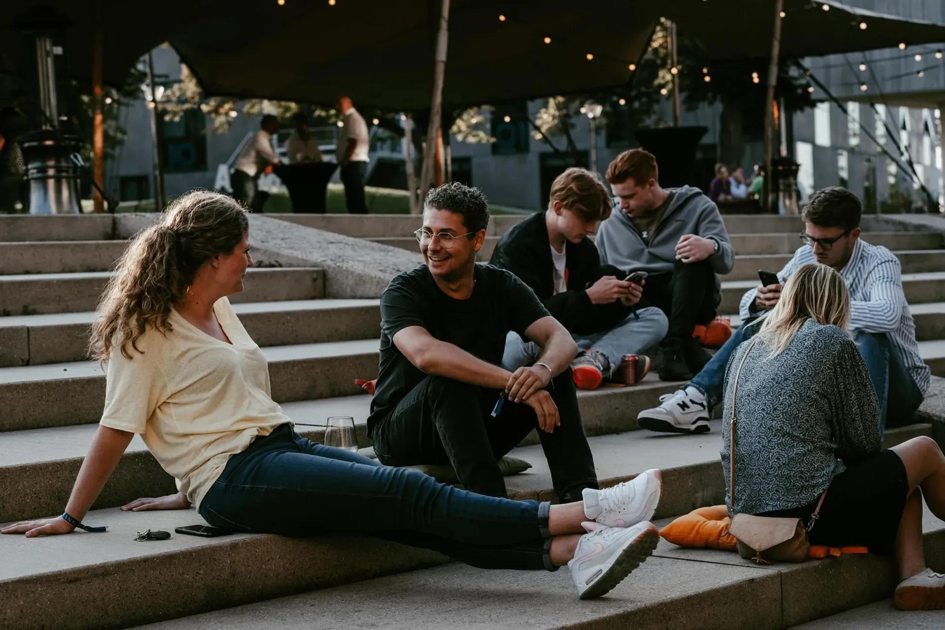 Medewerkers van de Triple O Campus in Breda die zitten op een trap en met elkaar praten
